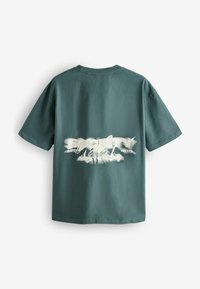 Tricou verde din bumbac, cu mâneci scurte, având un design stilizat cu text alb pe spate. Guler rotund cu o textură netedă și mată.