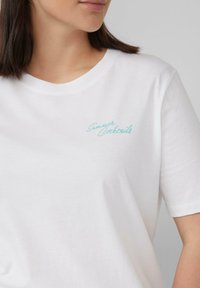 Witte katoenen t-shirt met een ronde halslijn en korte mouwen, versierd met turquoise borduursel met de tekst "Zomer Cocktails" op de borst.