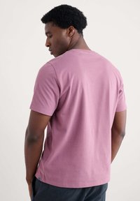 Roosa lühikeste varrukatega T-särk pehmest puuvillast, millel on ümar kaelus ja lamedad õmblused. Lihtne disain, ilma nähtavate mustrite või aktsendita.