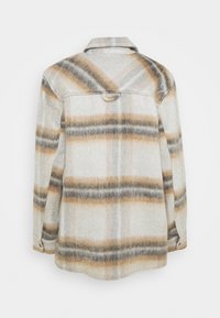 Flanellskjorta i vitt med brunt och grått rutigt mönster. Har krage, knäppning och en mjuk textur med avslappnad passform.