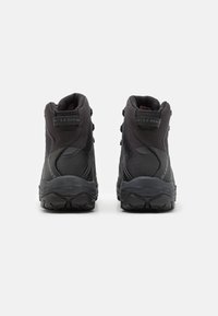 Bottes de randonnée noires avec un design montante, en maille et matériau synthétique, avec des accents texturés et une semelle en caoutchouc robuste. Présente un logo sur le talon.