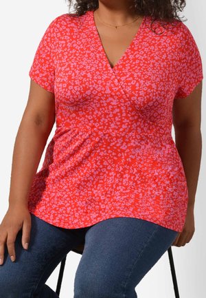 Červený top s krátkým rukávem, zdobený malým květinovým vzorem v světlejších odstínech. Měkká látka se zúženým pasem pro uvolněný střih.