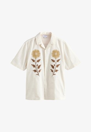 Flødefarvet kortærmet skjorte med knapper og krave, med symmetriske gyldengule og brune broderede blomsterdesigns på forstykkerne.