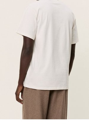 Korte mouwen, crèmekleurig katoenen T-shirt met een ronde hals, een soepele textuur en een relaxte pasvorm, gecombineerd met een bruine wollen broek.