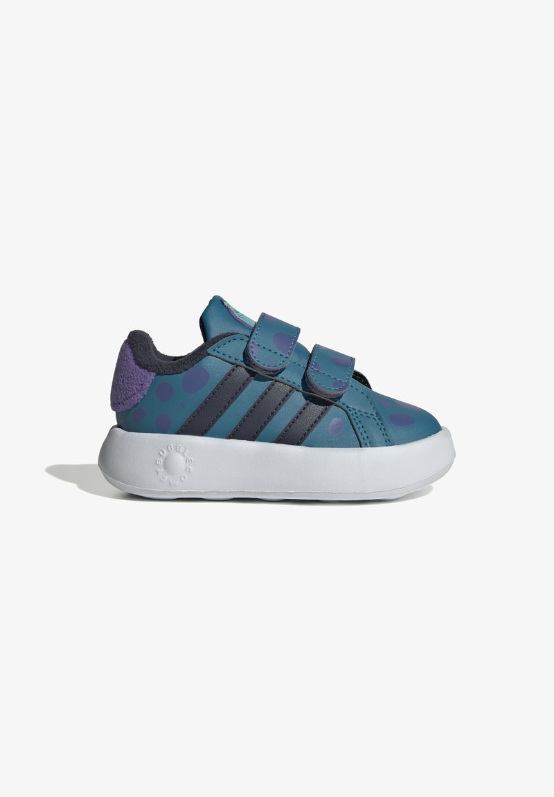 Zapatillas infantiles en azul y morado con correas de Velcro, estampado de lunares y suela de goma blanca. Material suave con acentos texturizados.