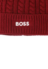 Czerwony dzianinowy beret z wzorem w warkocz i ściągaczem. Z przodu znajduje się biała haftowana napisana: "BOSS."