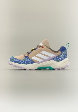 Scarpa da ginnastica Adidas beige e blu con strisce bianche, motivo pixelato verde e blu, dettaglio della suola color verde acqua e linguetta al tallone.