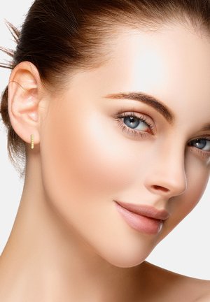 Gul hoop ørering med en subtil tekstureret design, båret i det venstre øre. Glat hud med et naturligt makeup look, lys baggrund.