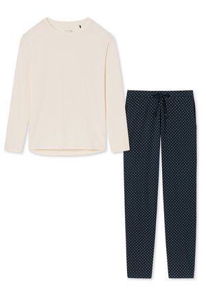 Långärmad krämfärgad topp med rund halsringning, i kombination med marinblå byxor med prickar och dragsko i midjan. Båda plaggen är tillverkade av mjukt tyg.