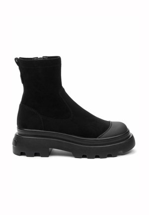 Bottes noires en nubuck avec une semelle en caoutchouc épaisse. Elles présentent un bout arrondi, des détails en panneau et une languette pour faciliter l'enfilage.
