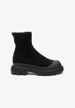 Zwarte enkelboots van suedine met een dikke rubberen zool. Bevat een ronde neus, paneeldetails en een trekhaak voor gemakkelijk aan- en uittrekken.