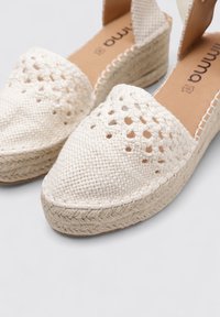 Espadrilles beige tejidas con punta cerrada, diseño de tejido abierto y suela de cuña envuelta en yute. Superficie de tela suave y acentos cosidos.