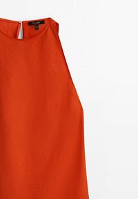Pomarańczowy bezrękawnik o gładkiej fakturze, z wycięciem w kształcie dziurki na plecach i subtelną boczną kieszonką.