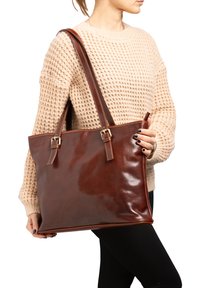 Bruine leren tote bag met een glanzende afwerking, stevige banden en metalen accenten. Beschikt over een rechthoekige vorm met een ruime binnenkant.