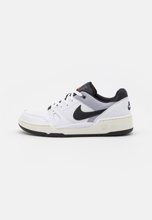 Weißer und grauer Sneaker mit niedrigem Schaft, schwarzem Nike-Swoosh, schwarzem Kragen, weißen Schnürsenkeln und offwhite Sohle auf einfachem Hintergrund.