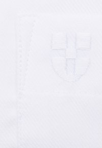 Biała tkanina z delikatnym teksturowanym splotem oraz wytłoczonym logo na środku, prezentująca czyste linie i minimalistyczny design.