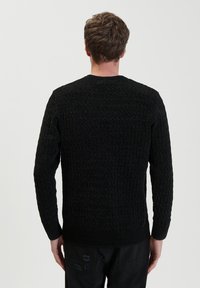 Maglione nero dalla texture in rilievo con collo rotondo a coste e maniche lunghe, con orlo aderente e motivo a nido d'ape.