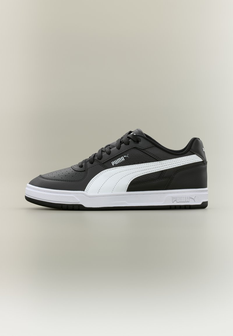 Μαύρο και άσπρο παπούτσι Puma χαμηλού προφίλ με κορδόνια και λευκή σόλα, εμφανιζόμενο από το πλάι σε ουδέτερο φόντο.