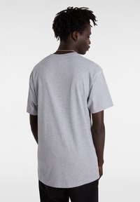 Una camiseta de algodón gris con mangas cortas, un escote redondo y un corte relajado, vista desde la parte de atrás. La textura parece suave.
