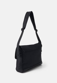 Borsa a tracolla nera realizzata in materiale liscio e resistente, con un design piatto, spallacci regolabili e chiusura a pattina.
