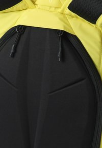 Mochila negra con superficie texturizada, detalles amarillos, cierre con cremallera y correas ajustables, destacando material duradero y diseño estructurado.