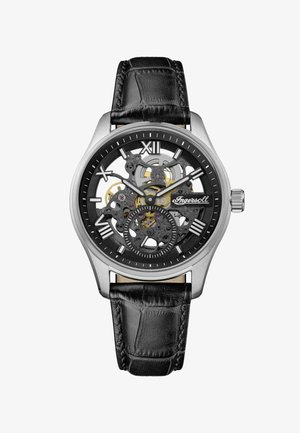 Svart läderrem klocka med ett hölje av silverfärgad rostfritt stål, skelett urtavla, svarta detaljer, romerska siffra markörer och guldfärgade detaljer.