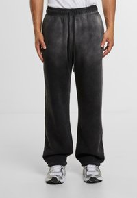 Pantalones de chándal negros, holgados, con una cinturilla elástica y cordón ajustable, que presentan una textura suave y un efecto de degradado suave.