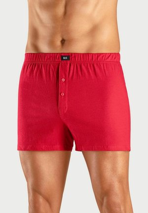 Men's red cotton boxer shorts with elastic waistband and two-button front fly, shown on a fit male torso and legs.