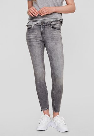 Gray denim skinny jeans with a faded finish, featuring a front button closure, five pockets, and paired with white sneakers.