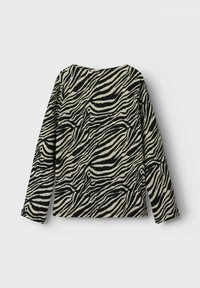 Top a maniche lunghe con stampa zebra in bianco e nero, caratterizzato da un tessuto testurizzato e un collo rotondo con una vestibilità comoda.