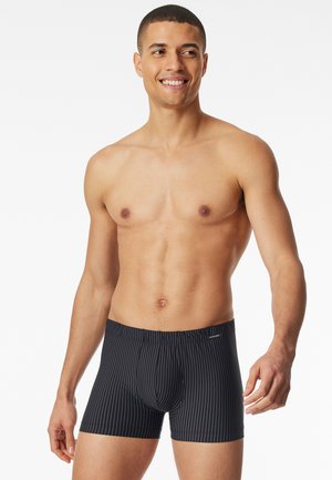 Black striped boxer briefs made of stretch fabric. Features a fitted design and elastic waistband with a logo accent. Smooth texture.
