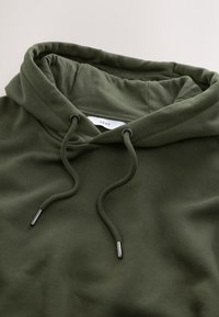 Ciemnozielona bluza z kapturem z sznurkami i metalowymi końcówkami, ukazująca kołnierz i górną partię klatki piersiowej.