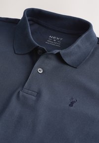 Marineblå poloshirt med krave, to knapper, broderet lille hjortelogo og trykt mærkat med størrelse medium og almindelig pasform.