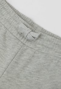 Grauer Stoffbund mit strukturiertem Finish und einem dekorativen Schleifendetail an der Vorderseite. Weiches und dehnbares Material, ideal für Komfort.