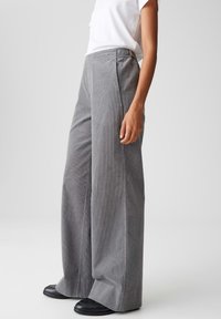 Grijze corduroy wijde broek met een gestructureerd oppervlak, voorzien van een hoge tailleband en zijzakken. Gepaard met zwarte schoenen.