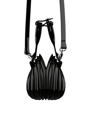 Sac à main noir brillant avec des nervures verticales sculptées, des poignées courtes et une bandoulière amovible, suspendu sur un fond blanc.