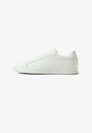 Witte lage sneaker met vetersluiting, gestructureerde stof en rubberen zool, gezien vanaf de buitenkant op een witte achtergrond.