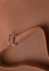 Brunt stof med en glat tekstur, der har en brun rem med en plastikklip. Materialet ser elastisk og tætsiddende ud.