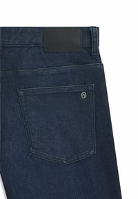 Tumma siniset farkut, joissa on sileä pinta. Musta nahkainen vyötärömerkki ja takataskussa hienovarainen logotunnus.