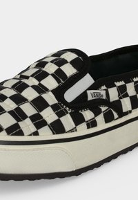 Черно-бял обувка Vans на плъзгане с горна част с възглавница, еластични странични акценти и бяла гумена подметка с текстуриран връх на пръстите.
