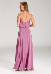 Długa, zwiewna sukienka z jasnoróżowego satyny, z głębokim dekoltem z tyłu, cienkimi ramiączkami i dopasowanym gorsetem, który przechodzi w luźną spódnicę.