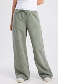 Light green wide-leg pants with vertical stripes, featuring an elastic waistband and drawstring. Made from a smooth, lightweight fabric.