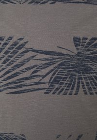 Szary materiał o teksturowanej powierzchni z granatowym wzorem palmowych liści. Wzór obejmuje wydłużone, abstrakcyjne kształty liści o różnej grubości.