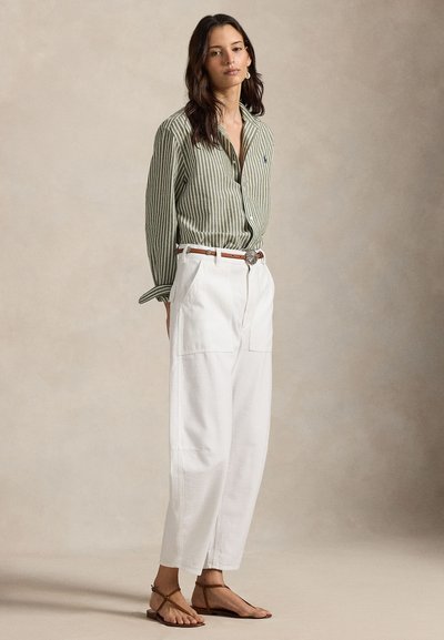 Grün gestreiftes Hemd mit Knopfleiste, weiße weite Hose mit Taschen, brauner Gürtel und braune flache Sandalen. Weiche Textur, legeres Design.