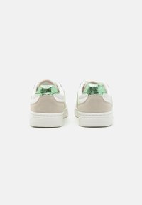 Baskets blanches et beiges avec un accent vert texturé au talon et un dessus lisse. Dotées d'une semelle rembourrée et d'un panneau en suède.