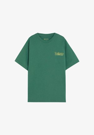 Groen T-shirt met korte mouwen en gele "Scalpers Company"-logo op de linkerborst en een ronde hals.