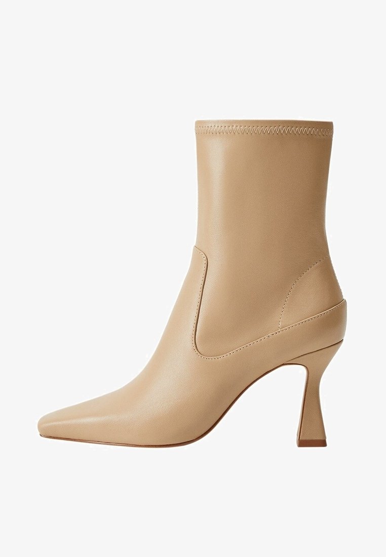 Beżowy skórzany botek do kostki z zaostrzonym noskiem, wąskim obcasem i elastyczną boczną wstawką; gładka faktura z minimalnymi detalami szwów.