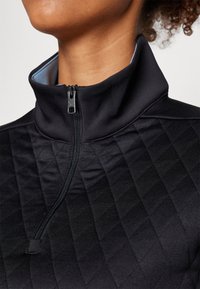 Černá zipová bunda s vysokým límcem, s prošívanou texturou a hladkým materiálem. Jemný modrý akcent uvnitř límce.