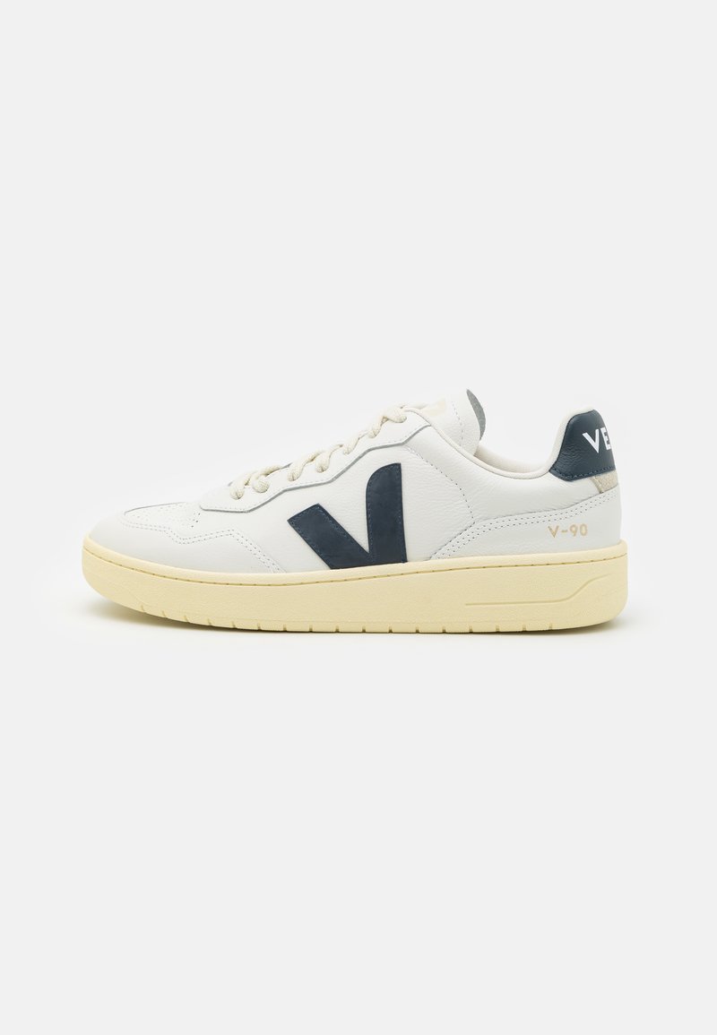 Weiße Ledersneaker mit navyblauen Akzenten, ausgestattet mit einer voluminösen Sohle, Schnürverschluss und auffälligem Seitenslogo. Strukturiertes Finish und minimalistisches Design.