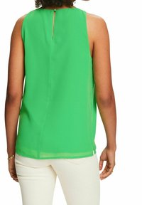 Blusa verde senza maniche con chiusura a bottoni sul retro, vestibilità leggermente ampia e spacchi laterali. Realizzata in un tessuto leggero e morbido.